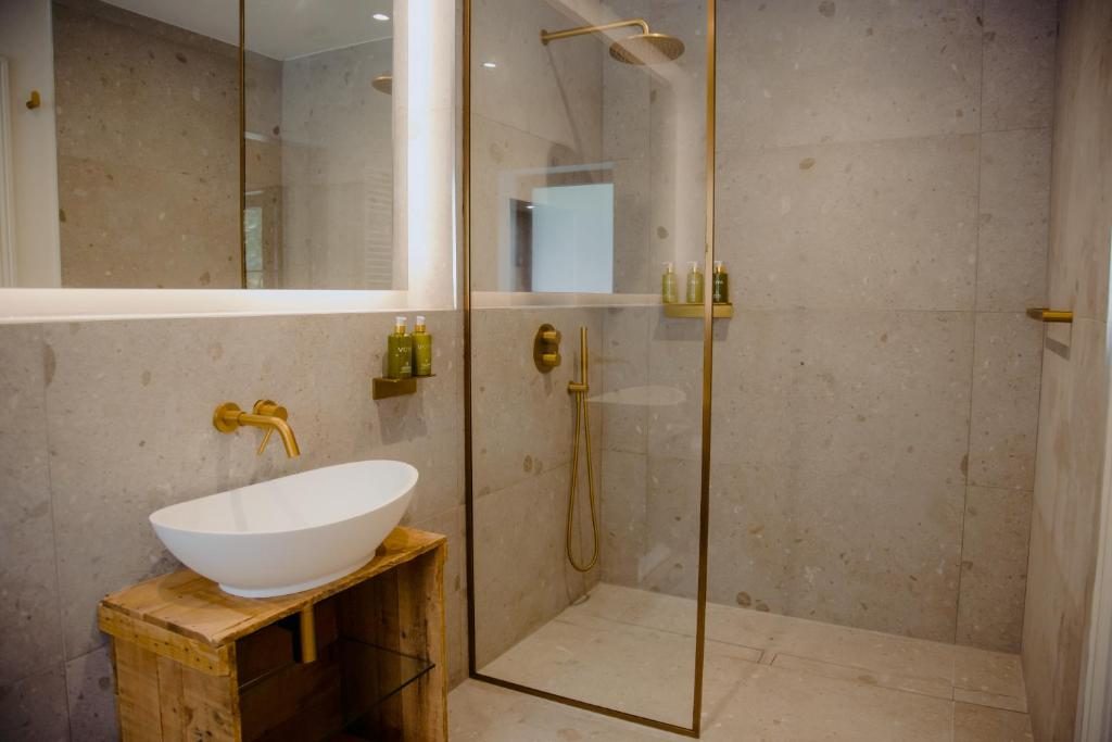 Stone-tiled ensuite with a brass rain shower in a Luxury Eco Cottage at The Deerstone.